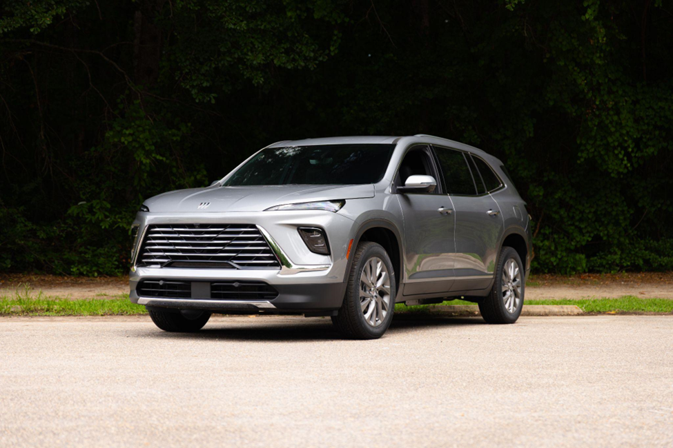 Silver Buick Enclave parked on a road with a forest backdrop.