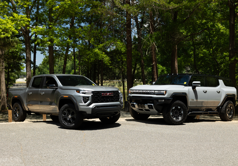 GMC Hummer EV and Canyon pakred in front of trees