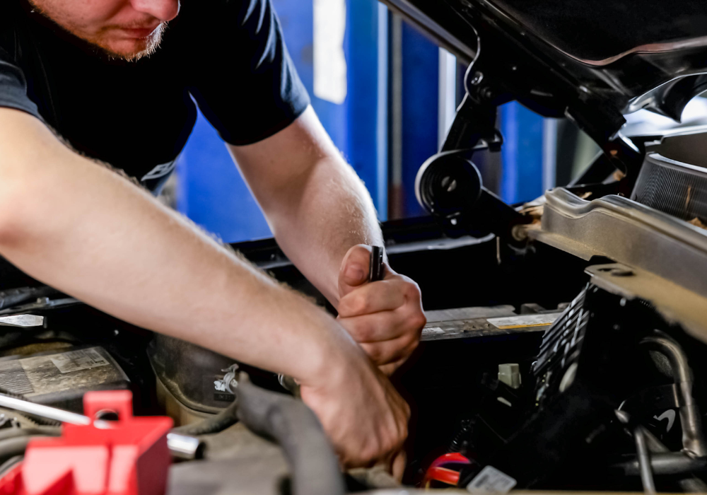 Flow service technician working on something underneath the hood of a car