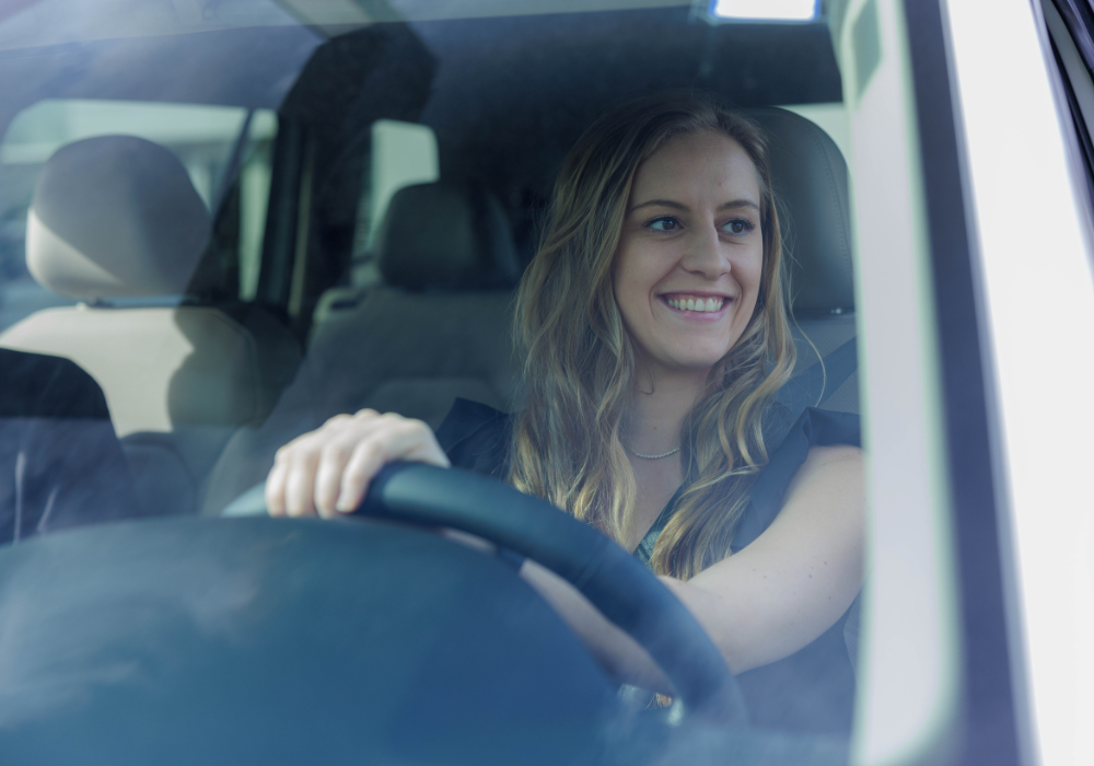 Customer sitting behind the steering wheel of a car and smiling