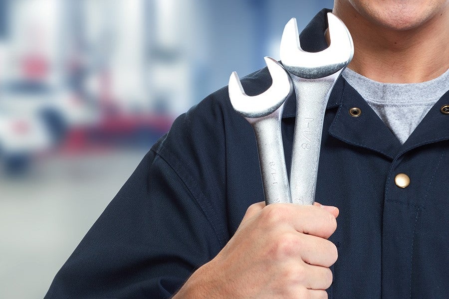 mechanic holding two large metal wrenches